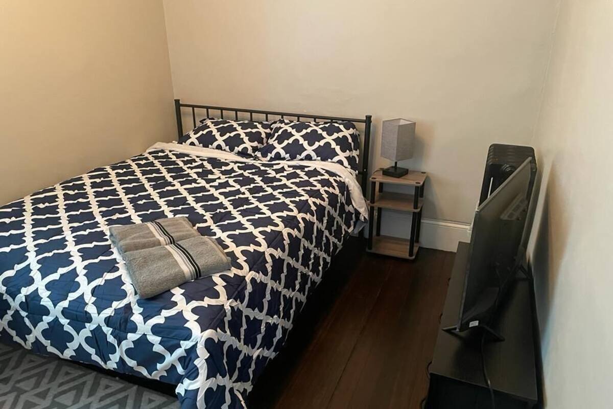 A bedroom with a bed, a nightstand, a lamp, and a TV.