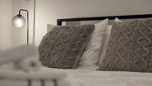Una cama bien hecha con una colcha blanca y dos almohadas con textura.