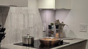 Una cocina moderna con estufa integrada, una olla en la estufa, y diversos utensilios de cocina y especias sobre la encimera.