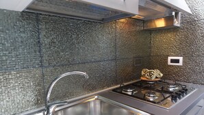 A modern kitchen with a stainless steel sink, a gas stove, and a textured backsplash.