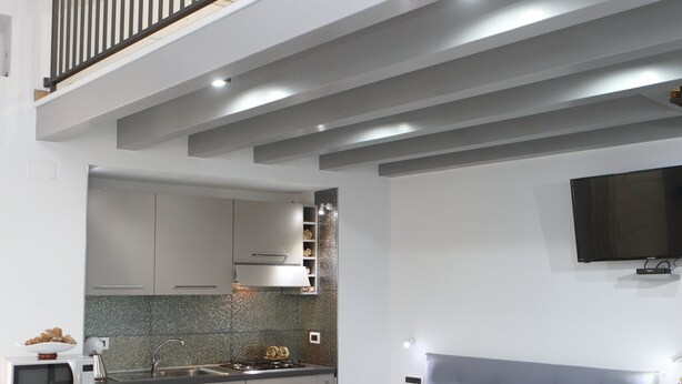 A modern apartment with a loft bedroom, a kitchen, and a dining area.