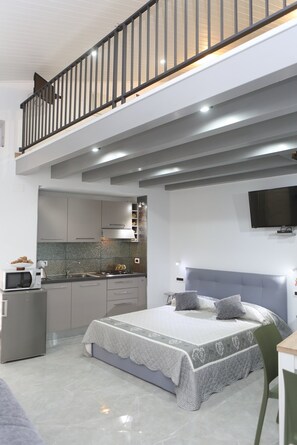 Un apartament modern amb un dormitori tipus loft, una cuina i una zona de menjador.