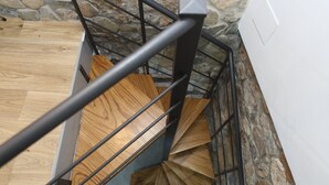 A staircase with wooden steps and metal railings, leading to a stone wall.