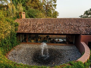 Une maison avec un toit en tuiles et une fontaine dans le jardin avant.