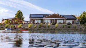A modern house with solar panels, a dock, and a landscaped garden by a lake. - Modern one bedroom in quiet lakeside retreat near wineries, dock, boats and more! (Zillah)