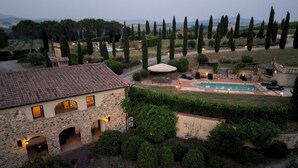 Un edificio de piedra con piscina, mobiliario exterior y vistas al campo.