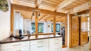 Eine Küche mit Holzbalken, einer weißen Arbeitsplatte und Blick ins Freie.