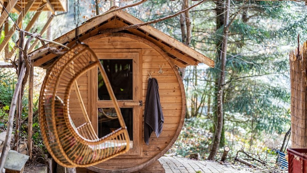 Eine Holzhütte mit einer runden Struktur, einem Schaukelstuhl und einer Tür, an der ein Handtuch hängt.