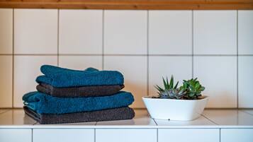 Gestapelde handdoeken en een potplant op een betegeld oppervlak.