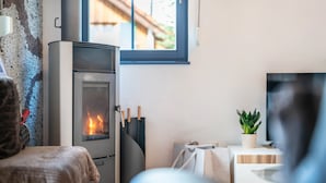 Ein gemütliches Zimmer mit Kamin, einem Bett, einem Fernseher und einem Fenster mit Blick auf ein Gebäude.