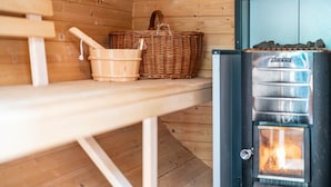 Ein Holz-Saunaraum mit einer Bank, einem Korbwannenstuhl und einem Holzofen.