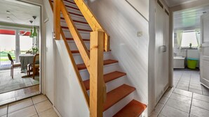 Una escalera con barandillas de madera y peldaños anaranjados que conducen a un piso superior.