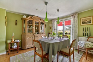 Un espace repas comprenant une table, des chaises, un buffet et une vue par la fenêtre.