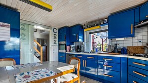 Una cocina con armarios azules, una mesa de madera y sillas.