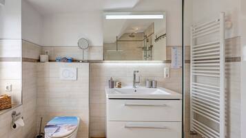 Een moderne badkamer met toilet, wastafel, spiegel en handdoekhouder.
