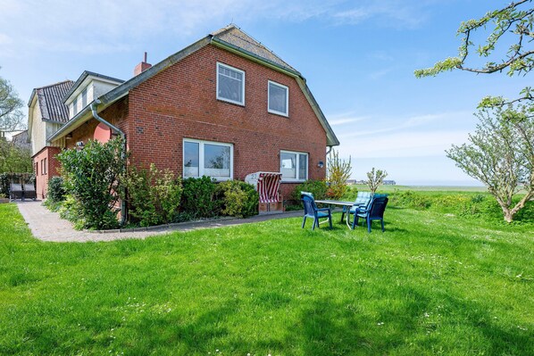 A two-story brick house with a patio, a flag, and a view of the countryside.