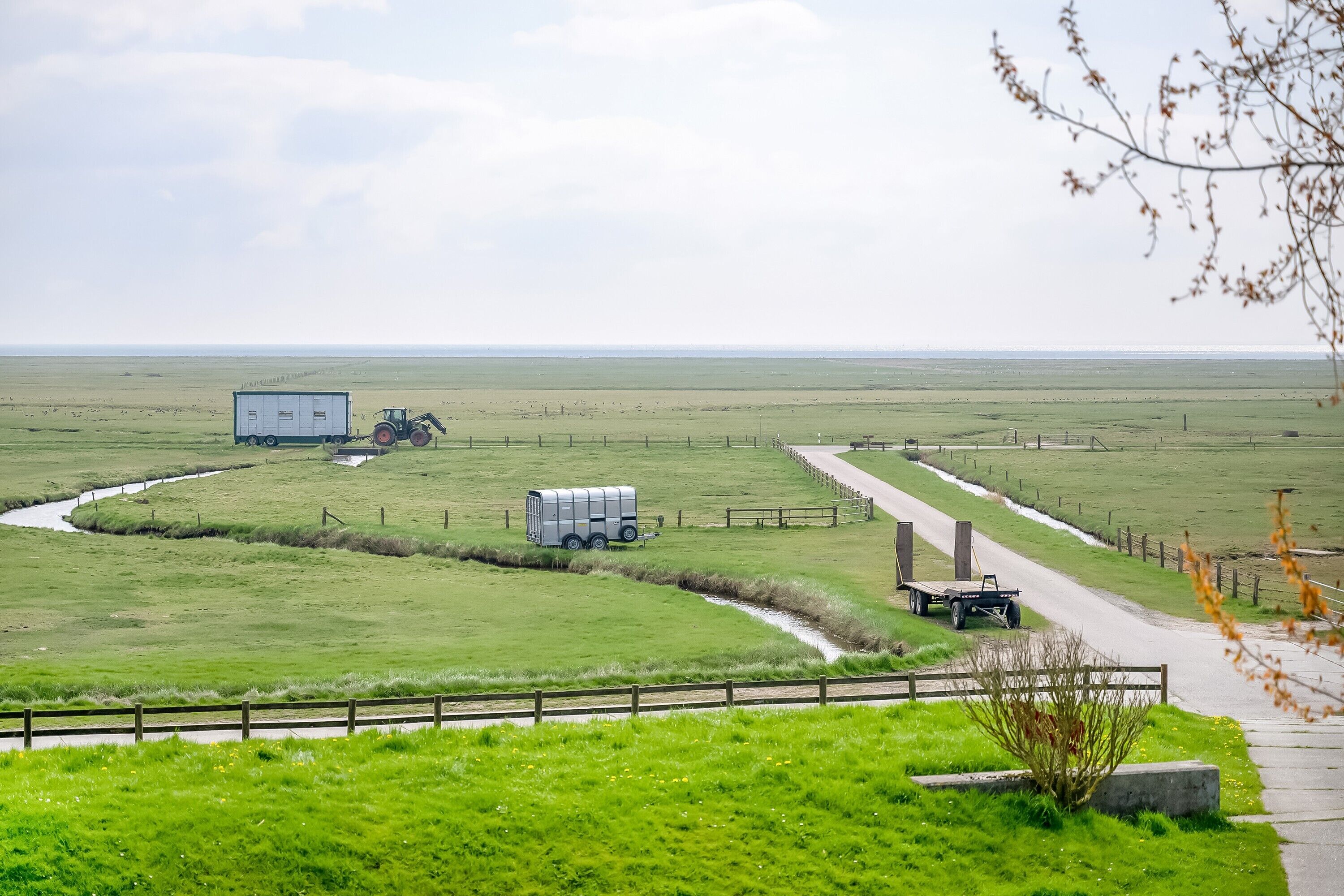 Ländliche Landschaft mit einer Straße, einem Wohnwagen und einem Traktor.