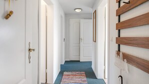 Un pasillo con paredes blancas, alfombra azul y listones de madera a la derecha.
