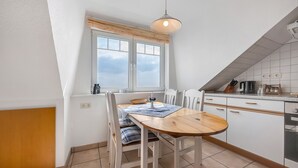 Una cocina con una mesa de comedor, sillas, un ventanal y una lámpara colgante.