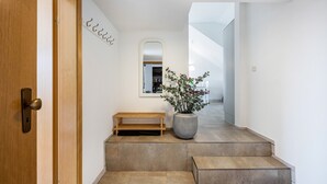 A hallway with a wooden door, a bench, a large potted plant, and a mirror on the wall. - Apartment 'Ferienwohnung Voglkoje' with Private Terrace, Shared Garden and Wi-Fi (Pellworm)