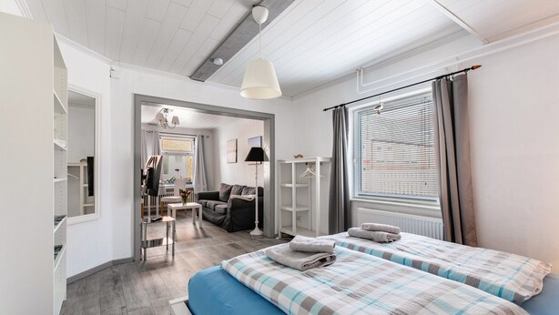 Una habitación de hotel moderna con una cama grande, un escritorio, una silla, un armario y un ventanal con cortinas.