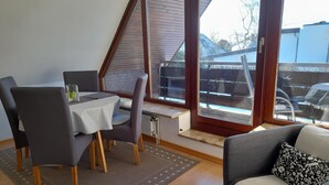 Ein Zimmer mit Esstisch, Stühlen, einer Couch und großen Fenstern.