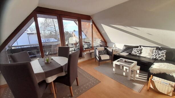 Ein modernes Loft-Schlafzimmer mit Essbereich, großen Fenstern und einer gemütlichen Sitzecke.