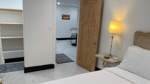Une chambre d’hôtel avec un lit, une table de chevet avec une lampe, une porte en bois et une vue sur la salle à manger.
