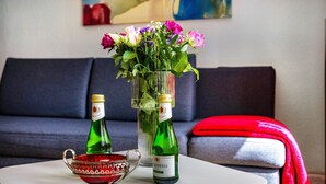 A living room with a sofa, a coffee table with decorative items, and a vase with flowers. - Apartment 'Halunder' with Private Garden and Wi-Fi (Leck)
