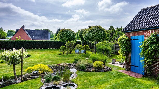 A well-maintained garden with a pond, various plants, and a blue door. - Apartment 'Halunder' with Private Garden and Wi-Fi (Leck)