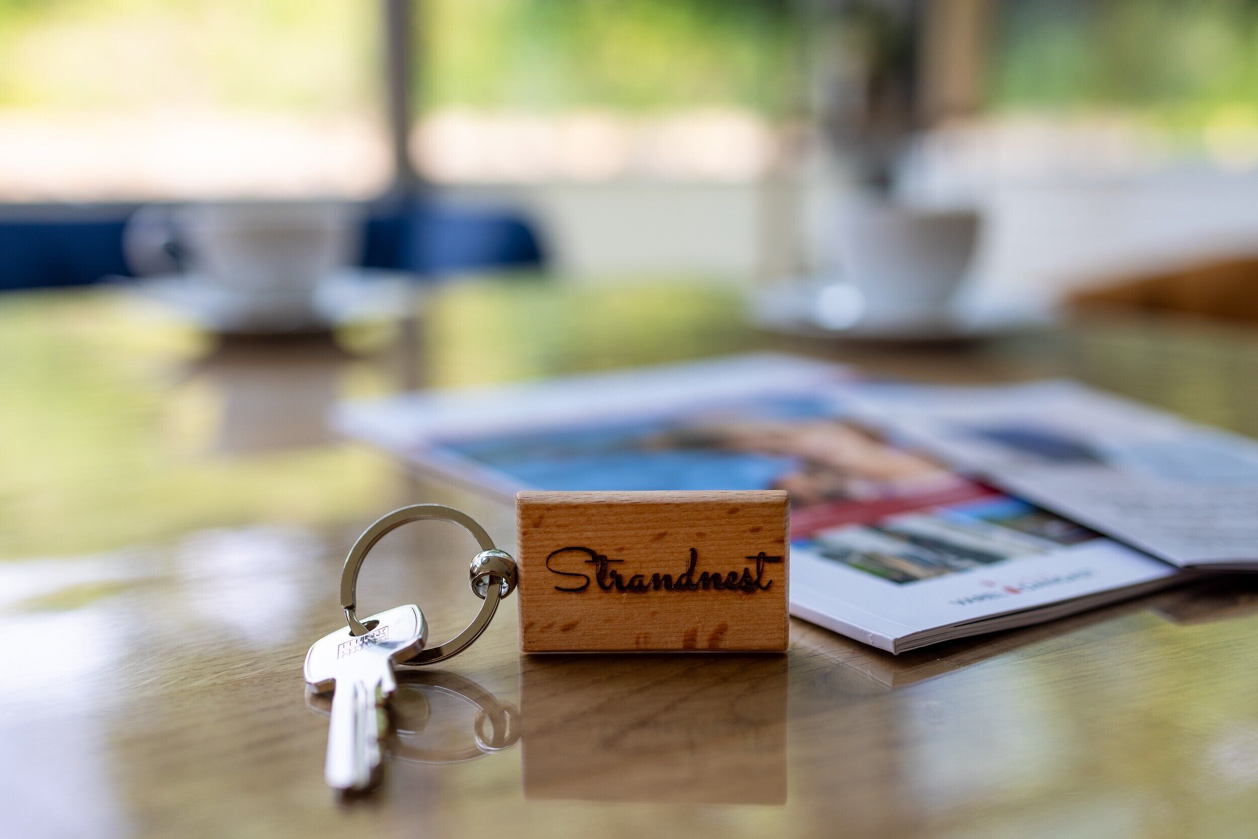 A wooden block with engraved text, a keychain, and a magazine on a table.