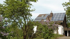 A house with solar panels on the roof, surrounded by greenery and trees. - Apartment 'Fernblick, 83 sqm' with Shared Terrace, Garden, and Wi-Fi (Bad Grund)