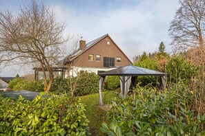 Une maison avec un jardin, un belvédère et une cheminée en briques.