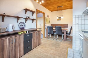 Une cuisine avec des meubles de rangement en bois, une machine à café et un coin repas comprenant des chaises et une table.