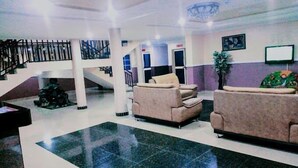 A lobby with a staircase, two sofas, a reception desk, and a large mirror. - Joscord Hotel  (Asokoro)