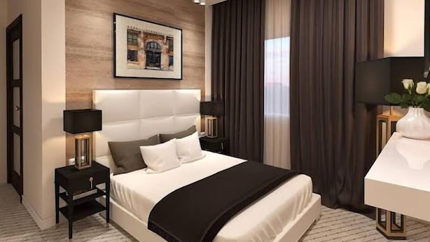 A modern hotel room with a large bed, two bedside tables, a desk, and a painting on the wall. - Joscord Hotel  (Asokoro)