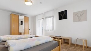 A bedroom with a bed, a desk, a chair, a mirror, and artwork on the wall. - Ferienhof Brutoni Apartment "Schwarzwaldtraum" with Mountain View, Balcony, Shared BBQ Area (Bad Peterstal-Griesbach)