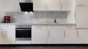 A modern kitchen with white cabinets, a stainless steel oven, a black range hood, and a coffee maker. - Ferienhof Brutoni Apartment "Schwarzwaldtraum" with Mountain View, Balcony, Shared BBQ Area (Bad Peterstal-Griesbach)