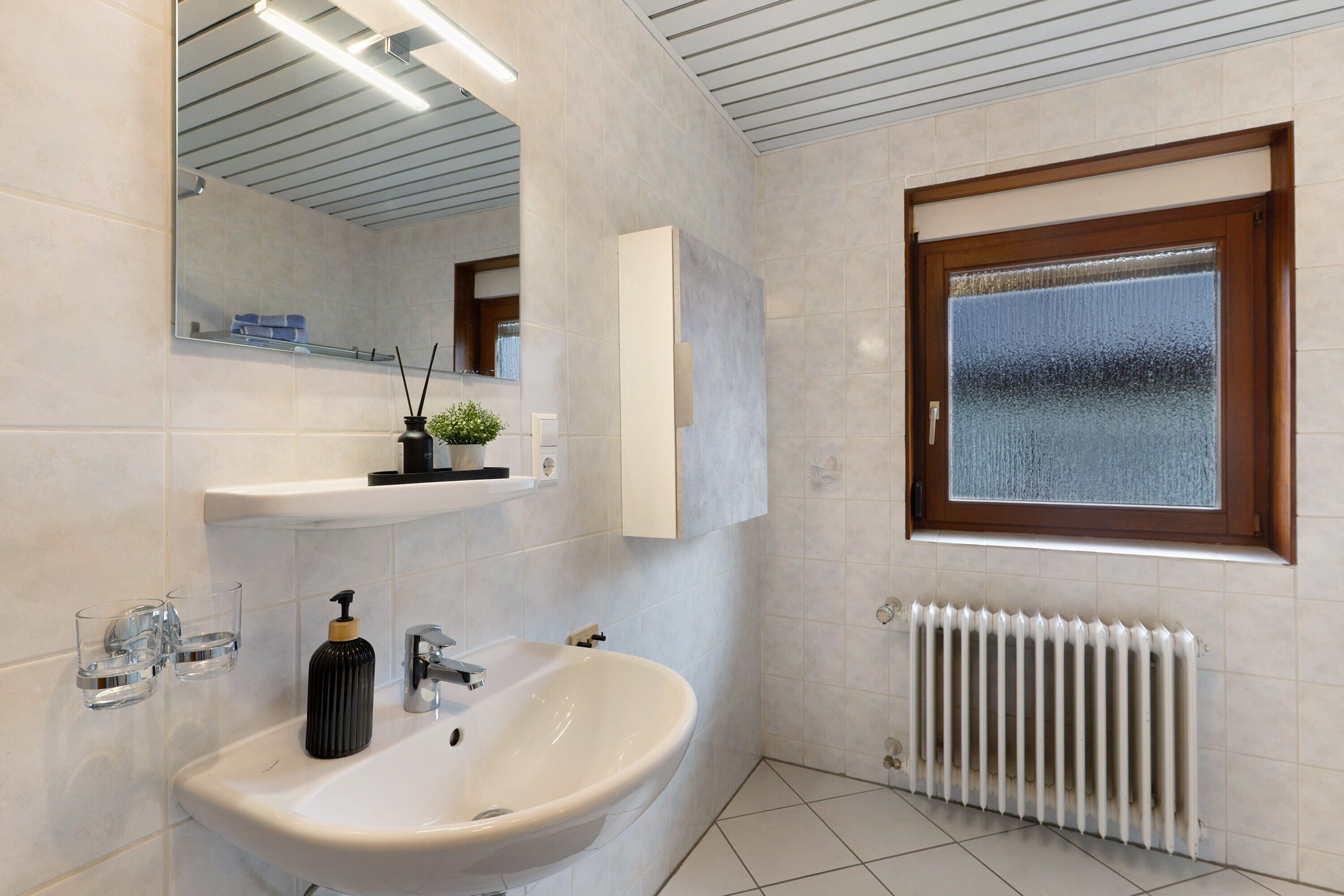 Une salle de bain moderne avec un lavabo, un miroir et une fenêtre.