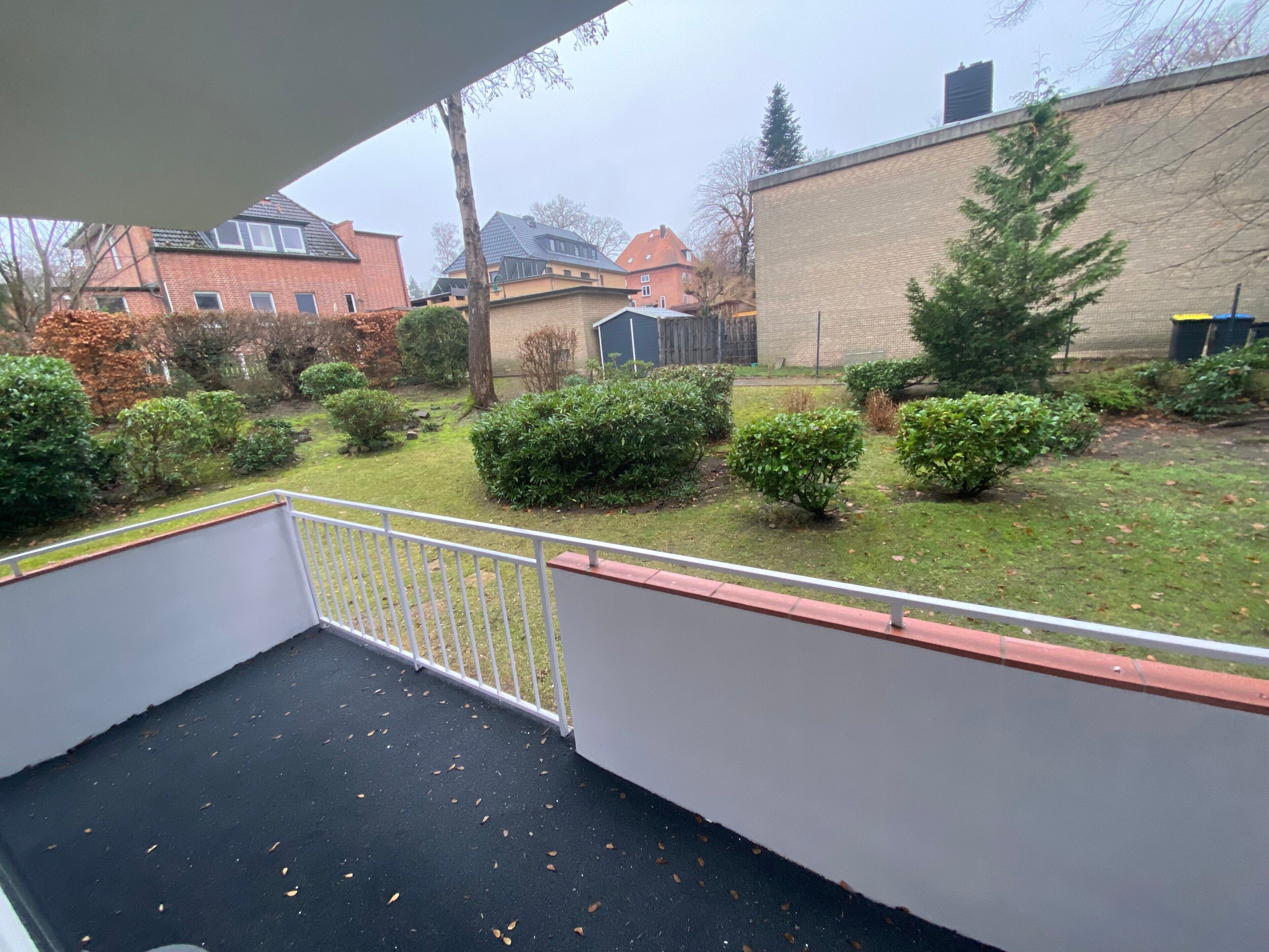 Un balcón con vistas a una zona residencial, que incluye casas y un edificio grande.