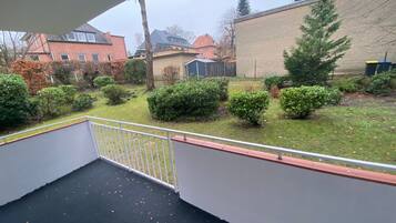 Un balcón con vistas a una zona residencial, que incluye casas y un edificio grande.