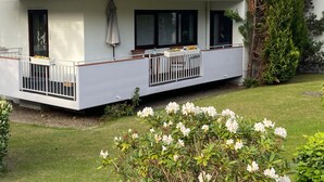 Un immeuble de deux étages doté de balcons, d’un petit jardin et d’un arbre.