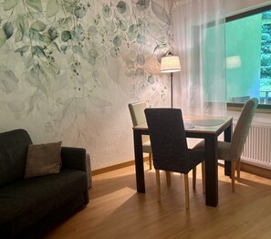 Ein Zimmer mit Esstisch, Stühlen, einer Couch, einer Lampe und einem Fenster mit Blick.