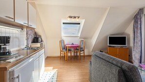 A compact living space with a kitchenette, dining area, and a television.