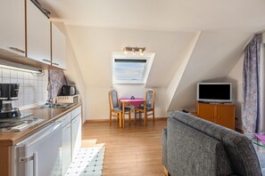 A compact living space with a kitchenette, dining area, and a television.