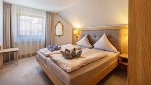 Ein Hotelzimmer mit einem großen Bett, einem Nachttisch, einem Spiegel und einem Fenster mit Vorhängen.