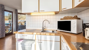 Eine moderne Küche mit weißen Schränken, einer Edelstahl-Spüle, einer Mikrowelle und einem Toaster.