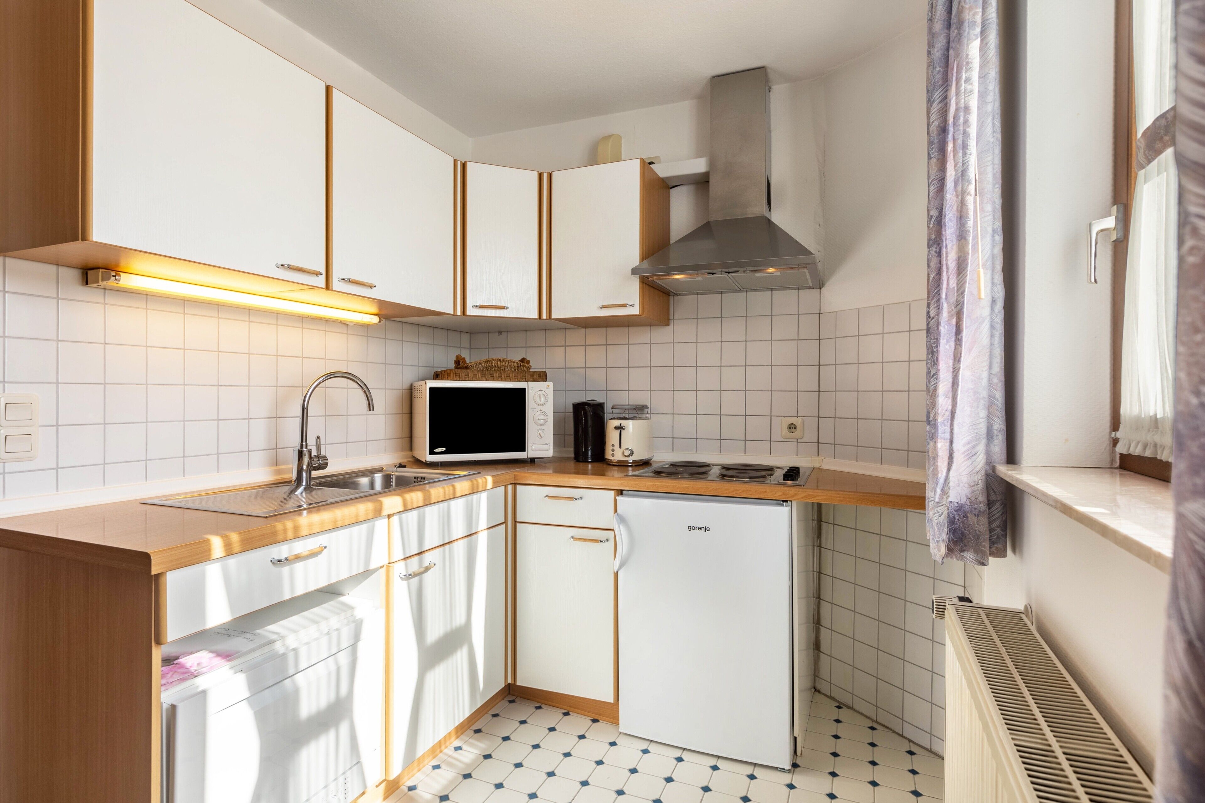 A compact kitchen with white cabinets, a microwave, a toaster, and a dishwasher.