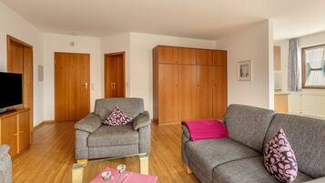 Ein Wohnzimmer mit zwei grauen Sofas, einem Holzschrank und einem Fernseher.