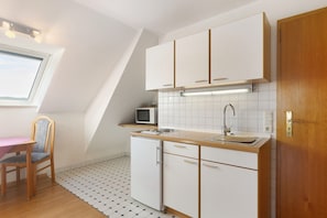 A compact kitchen with a microwave, sink, and wooden cabinets. - Apartment 'Eimberg 8' with Balcony (Willingen (Upland))